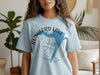 Light blue t-shirt with a blue Rushford Lake map over a compass graphic.