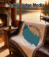 Lake McConaughy Nebraska map blanket on a leather couch with a fireplace and lake view.