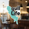 Turquoise silhouette of a lake with text "gull life" in black, on a window.