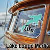 Turquoise map on boat window reads "Arcadia Life." "Lake Lodge Media" text below.