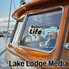 Rabun Life and Lake Lodge Media logos on a boat window with wood trim.