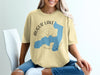 Augur Lake New York graphic on a light yellow t-shirt with compass and lake outline.