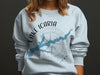 Light blue sweatshirt with Icaria Lake Iowa map and compass graphic.
