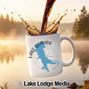 White mug with "Lake Quivira" and a compass design, with coffee pouring in.