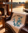 Woven blanket with "Lake Martin Alabama" map graphic on a leather couch.