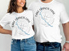 Two people wearing white t-shirts with "Lake Francis Case South Dakota" and a compass map.