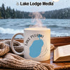 White mug with blue Lake Pulaski outline and compass on a rainy day.