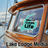 Turquoise sticker "Merrill Creek Life" on a boat window next to "Lake Lodge Media" text.