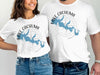 Two people model white t-shirts with a blue Lake Cachuma map and compass design.