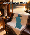 Blanket with Cain Lake map design and compass rose on a leather couch.