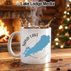 White mug with Sand Lake Ontario map and compass design, splashing coffee.