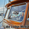 Wood-paneled boat window with "Apache Life" sticker and "Lake Lodge Media" text.