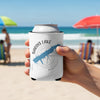 White can koozie with blue Sardis Lake, Mississippi map and compass design held on beach.