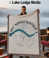 Woven blanket with Lake Minnewanka map and compass design, held by a man.