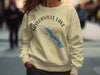 Saylorville Lake Iowa graphic on a light yellow sweatshirt over a compass rose.