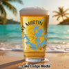 Pint glass of beer with "Lake Martin" and Alabama outline design on beach.