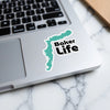 Turquoise map sticker with "Baker Life" text on a laptop keyboard.