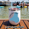 A white insulated wine tumbler featuring an Emerald Lake Canada graphic rests on a wooden boat deck with people swimming in the background.