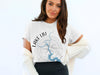 Woman wearing a white t-shirt with a compass graphic and "Lake LBJ Texas" text.