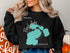Black sweatshirt with teal Floyd Lake map design and compass rose.
