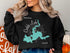 Black sweatshirt with a teal map of Caddo Lake, Texas, and compass graphic.