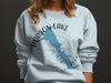 Light blue sweatshirt with "HUDSON LAKE" and a blue map over a compass rose.