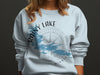 Light blue sweatshirt with Rainy Lake, Minnesota map and compass graphic.