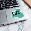 Teal sticker with "Emerald Life" text on a laptop keyboard.