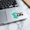 Teal lake silhouette sticker with "Pleasant Life" text on laptop.