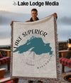 Man holding a Lake Superior map blanket with Wisconsin text and a compass graphic.