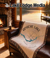 Woven blanket with Apache Lake map design draped on a leather couch.