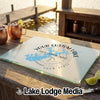 A custom tempered glass cutting board with a lake map design on a wooden dock.
