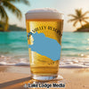 Glass of beer with "BOND VALLEY RESERV" and a blue map shape, on a beach.