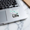 Burnsville Life sticker on a laptop keyboard with a teal map outline.