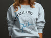Light blue sweatshirt with Mitchell Lake Alabama map and compass graphic.