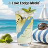 Glass of green bay drink with mint, lime, and ice on beach background.