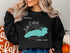 Black sweatshirt with a teal map of Lake Ontario and compass rose graphic.