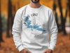 White sweatshirt with Rainy Lake Minnesota graphic and compass design.