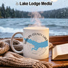 White mug with "Harlan County Lake Nebraska" design, steaming, by a window.