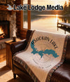 Throw blanket with Ashokan Lake map and compass design on a leather sofa.