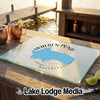 A glass cutting board featuring a blue map of Walden Pond rests on an outdoor wooden bar.