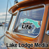 "Rainbow Life" sticker on a wooden boat with "Lake Lodge Media" text below