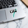 Sticker with teal lake outline and "Greenwood Life" text on a laptop.