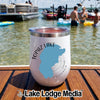 A white insulated wine tumbler featuring a Topaz Lake California graphic rests on a wooden surface with a lake and boats in the background.
