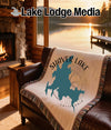 Woven throw blanket with Shaver Lake, California map design on a leather couch.