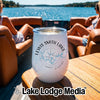 A white tumbler with a compass and lake design sits on a wooden boat table.