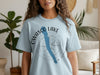 Light blue t-shirt with "Owsco Lake" text and compass graphic overlaid.