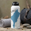 White water bottle with lake graphic and "LAKE WASHINGTON" text, by a travel bag.