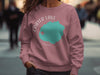 Rose sweatshirt with a teal Crater Lake, Oregon graphic and compass design.