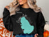 Black sweatshirt featuring a teal map outline of Ossipee Lake, New Hampshire.